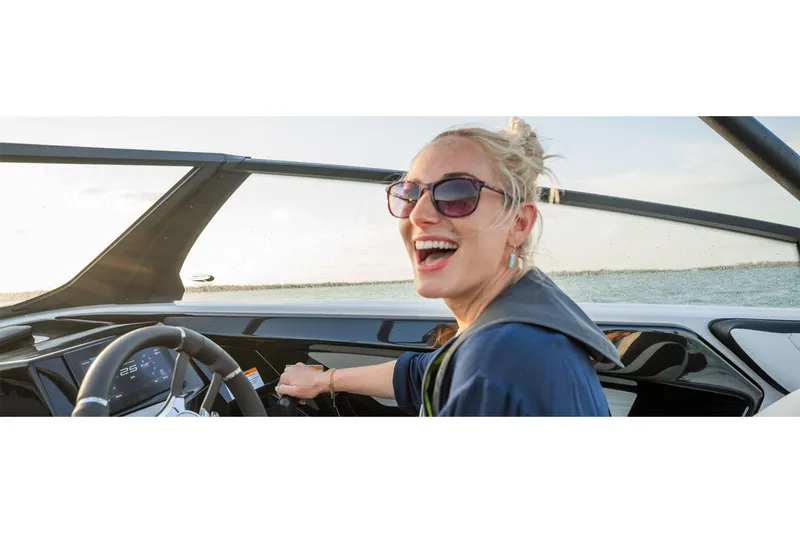 Slide: The Image of Smiling woman driving 2025 Yamaha Boats 222S, enjoying a sunny day on the water. - 8