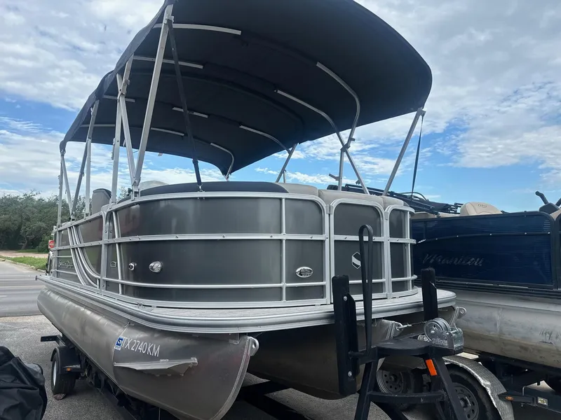 Slide: The Image of 2022 South Bay 222RS LE pontoon boat with canopy on trailer, under cloudy sky. - 1