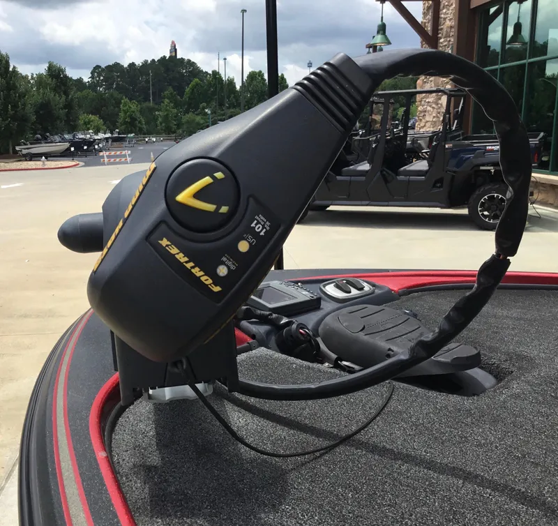 Slide: The Image of Trolling motor on a 2013 Nitro Z8 boat, parked outdoors with trees in the background. - 7