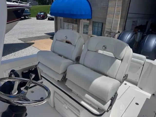 Slide: The Image of 2017 Edgewater 262CC boat interior with dual white captain's chairs and steering wheel. - 10