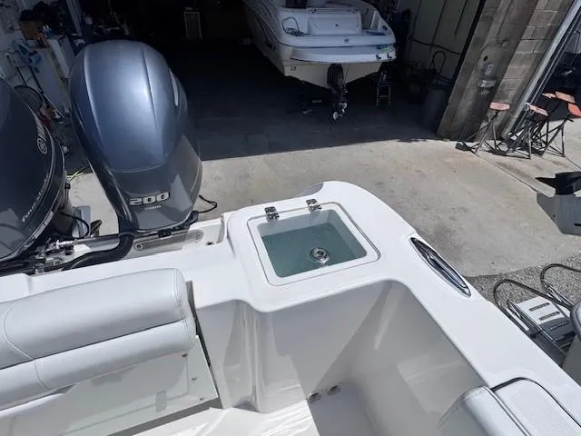 Slide: The Image of 2017 Edgewater 262CC boat with dual engines and a livewell in a garage setting. - 13