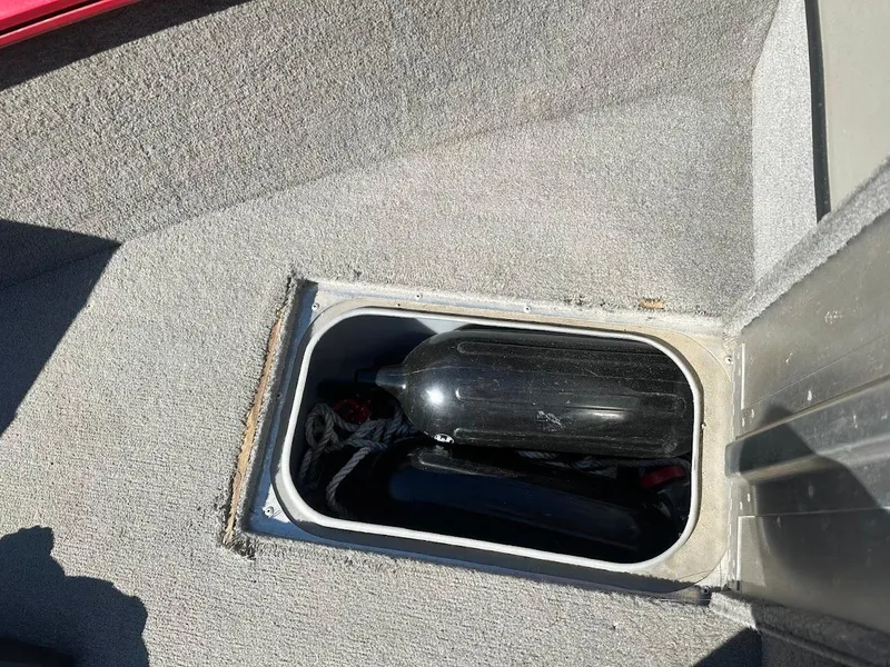 Slide: The Image of Storage compartment in 2013 Tracker Pro Guide V-175 SC boat, containing a black fender and rope. - 28