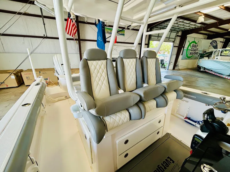 Slide: The Image of 2022 Everglades 365 Center Console boat interior with luxurious seating in a showroom. - 16