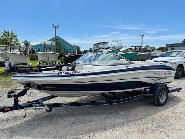 The Image of 2006 Tahoe Q4 Sport Fish boat on trailer, parked outdoors under clear blue sky. - 1