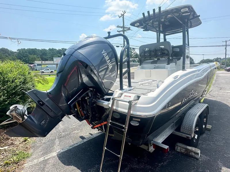 Slide: The Image of 2023 NauticStar 251 Hybrid boat engine and deck, surrounded by greenery. - 30