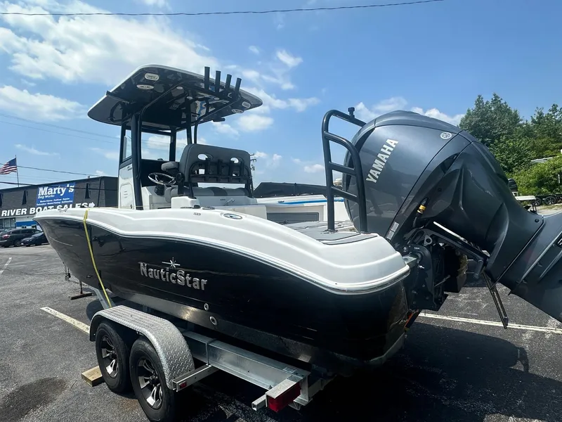 Slide: The Image of 2023 NauticStar 251 Hybrid boat interior with seating and console, parked in a marina. - 31