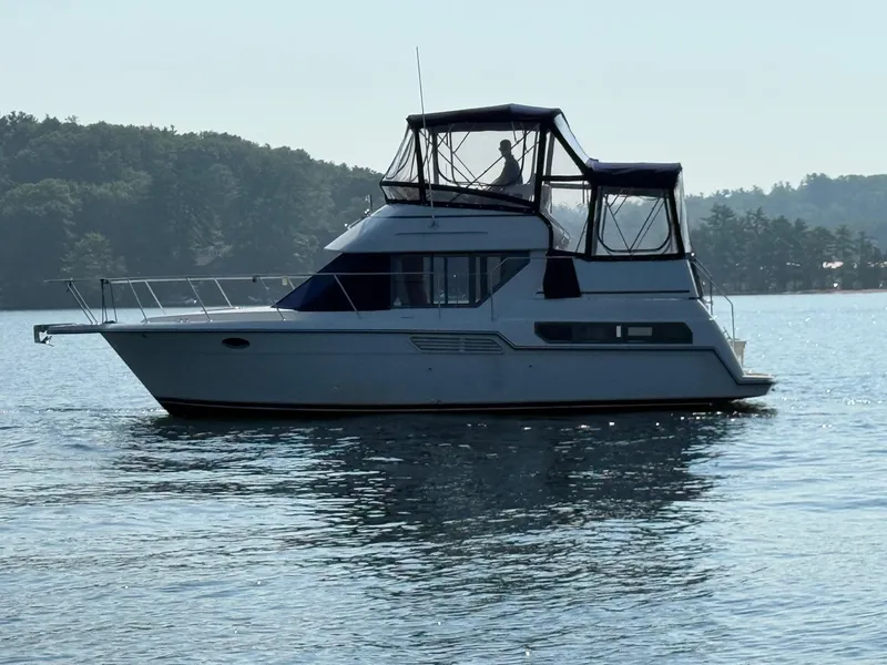 Slide: The Image of 1995 Carver 325 Aft Cabin yacht on calm water, surrounded by trees. - 10