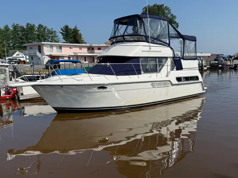 Slide: The Image of 1995 Carver 325 Aft Cabin yacht docked in a marina, reflecting on calm water. - 11