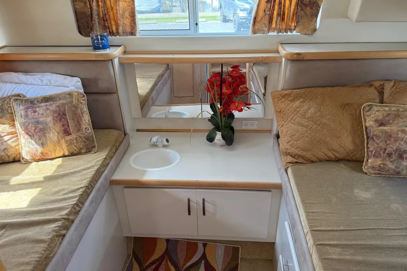 Slide: The Image of 1995 Carver 325 Aft Cabin interior with twin beds, decorative pillows, and floral arrangement. - 15