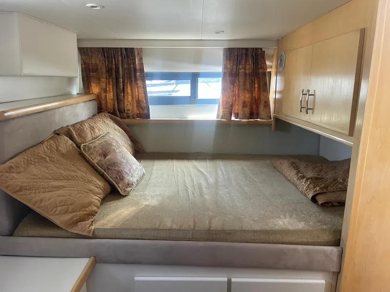 Slide: The Image of 1995 Carver 325 Aft Cabin interior with cozy bed, pillows, and wooden cabinetry. - 6