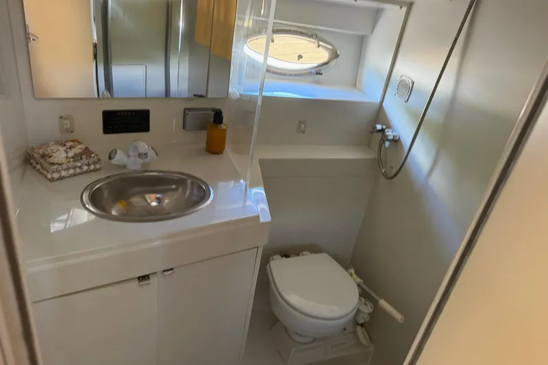 Slide: The Image of 1995 Carver 325 Aft Cabin bathroom with sink, toilet, and porthole window. - 22
