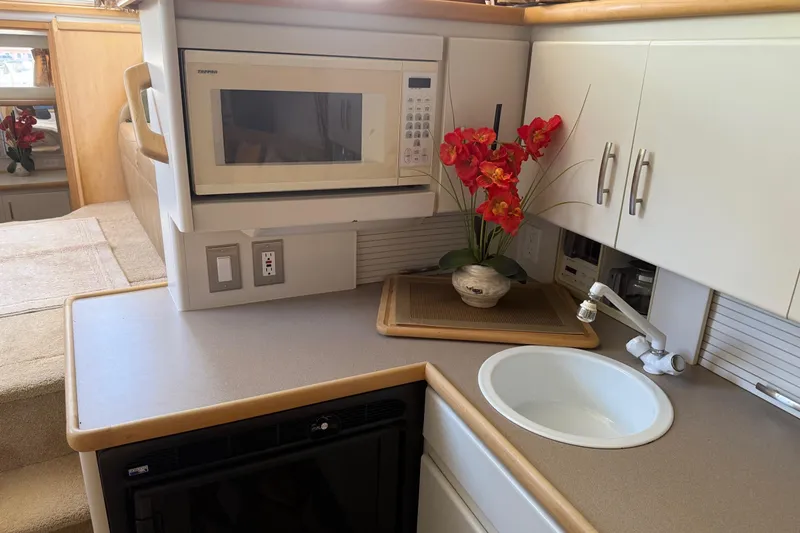 Slide: The Image of 1995 Carver 325 Aft Cabin kitchen with microwave, sink, and red flowers. - 23