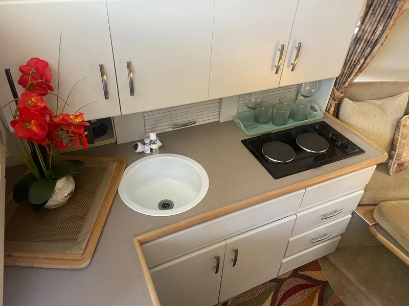 Slide: The Image of 1995 Carver 325 Aft Cabin kitchen with sink, stove, and floral decor. - 3