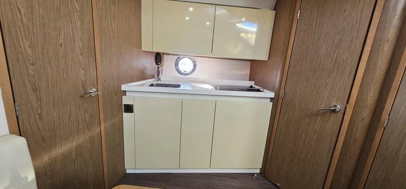 Slide: The Image of Interior of 2015 Beneteau 38 Gran Tourismo yacht, featuring a compact kitchenette with wood accents. - 18