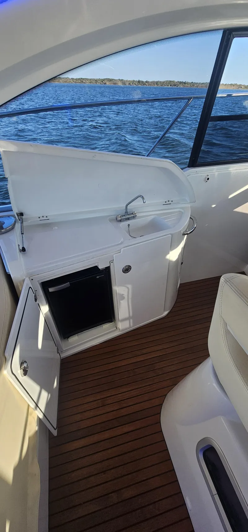 Slide: The Image of 2015 Beneteau 38 Gran Tourismo yacht interior with open cabinet, wooden flooring, and ocean view. - 9