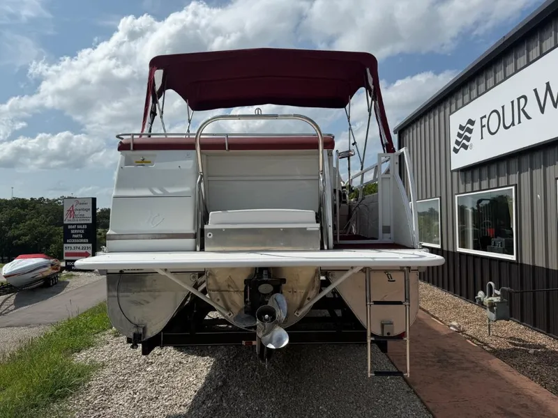 Slide: The Image of 2006 JC 266 TriToon Classic I/O boat with maroon canopy, parked near dealership. - 5