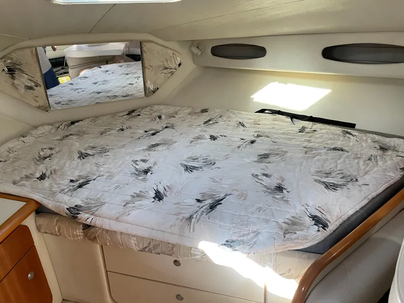 Slide: The Image of 1999 Wellcraft 3600 Martinique cabin interior with patterned bedding and mirrored accents. - 10