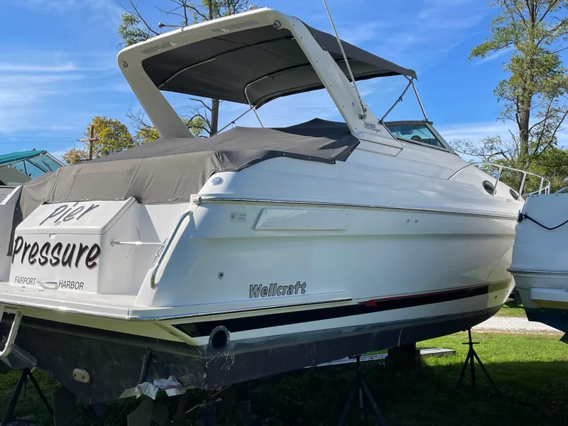 Slide: The Image of 1999 Wellcraft 3600 Martinique boat on stands, covered, with "Pier Pressure" text. - 2