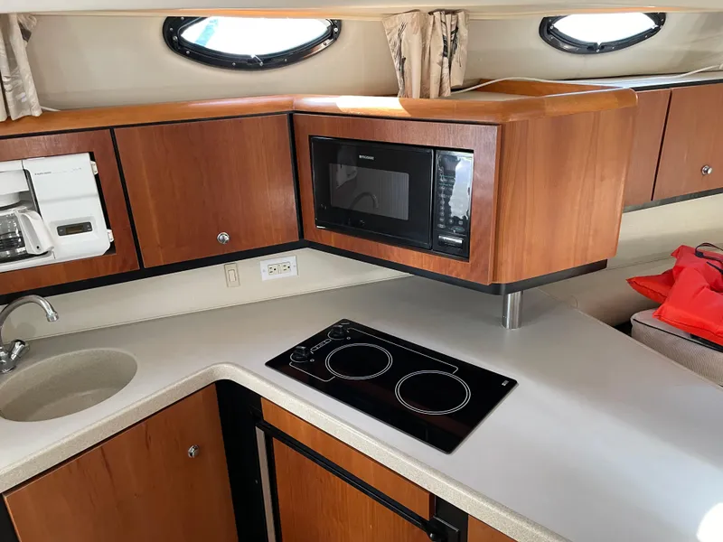 Slide: The Image of 1999 Wellcraft 3600 Martinique yacht kitchen with microwave, stovetop, and wooden cabinetry. - 7