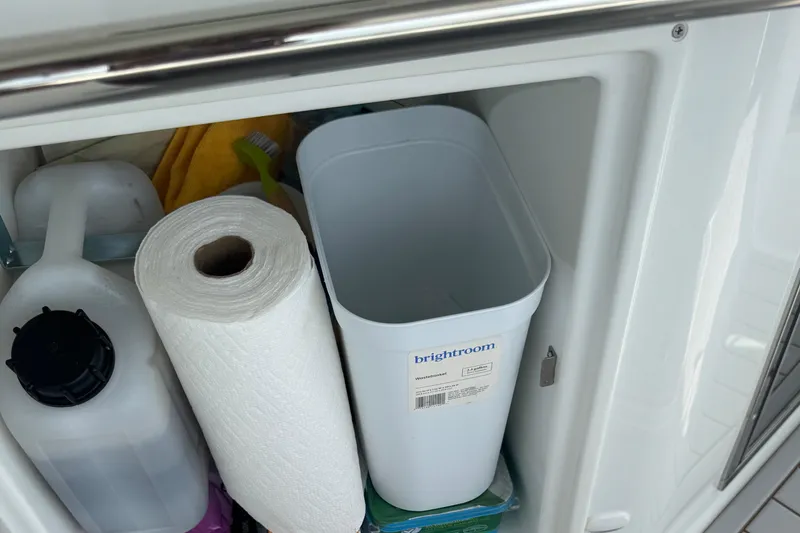 Slide: The Image of Storage compartment on 2023 Beneteau Gran Turismo 32 with paper towels and cleaning supplies. - 14