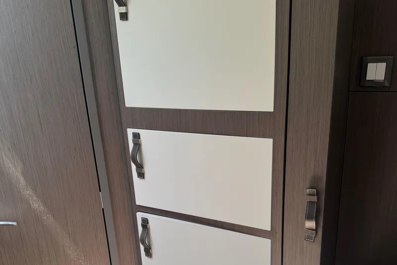 Slide: The Image of Interior cabinetry of 2023 Beneteau Gran Turismo 32 yacht, featuring sleek wood and white panel design. - 23