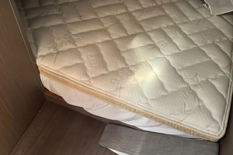 Slide: The Image of Mattress in 2023 Beneteau Gran Turismo 32 cabin, featuring quilted design and wooden flooring. - 24