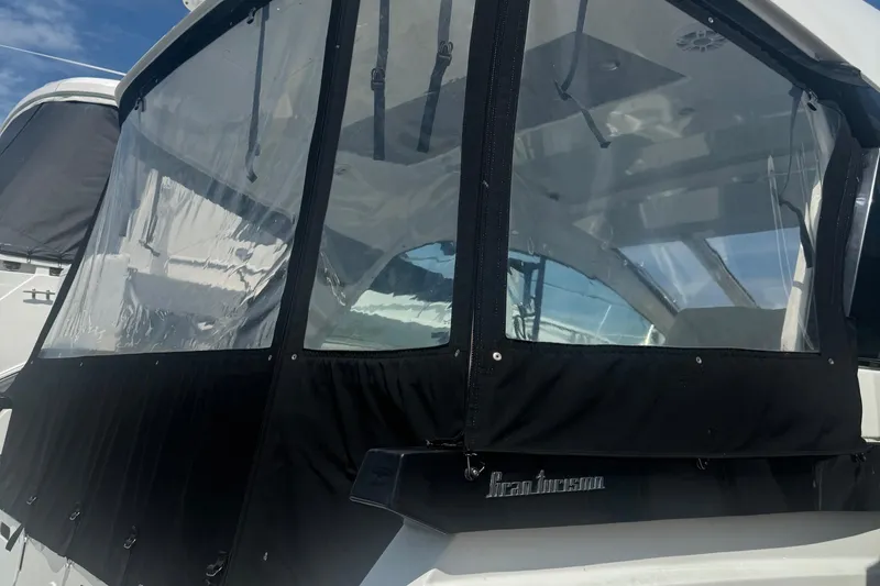 Slide: The Image of 2023 Beneteau Gran Turismo 32 with clear enclosure and black trim under blue sky. - 8