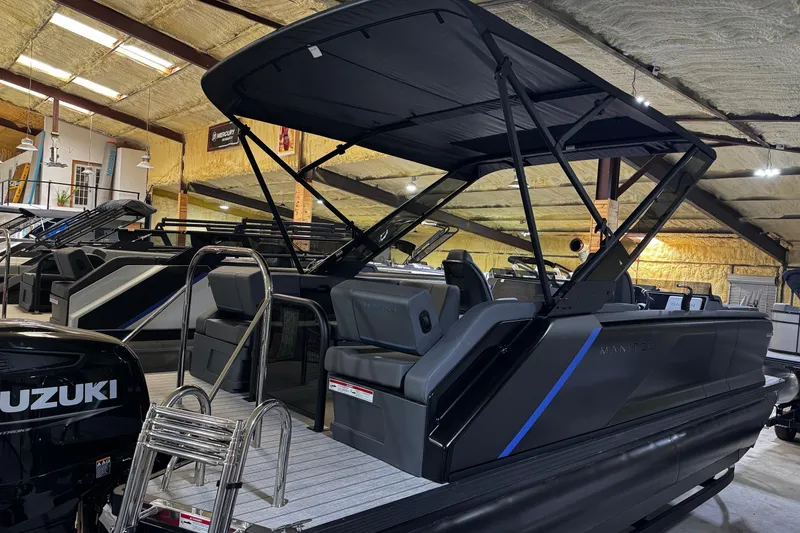 Slide: The Image of 2025 Manitou Explore boat in showroom, featuring sleek design and Suzuki engine. - 2