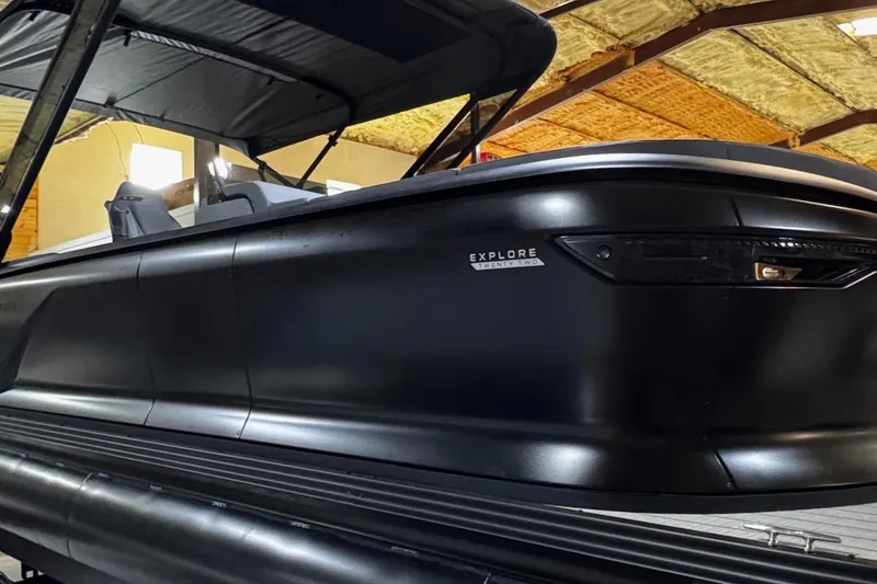 Slide: The Image of 2025 Manitou Explore boat in a warehouse, showcasing sleek black design and modern features. - 3