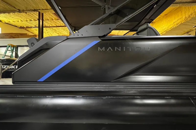 Slide: The Image of 2025 Manitou Explore boat with sleek black design and blue accent stripe. - 8