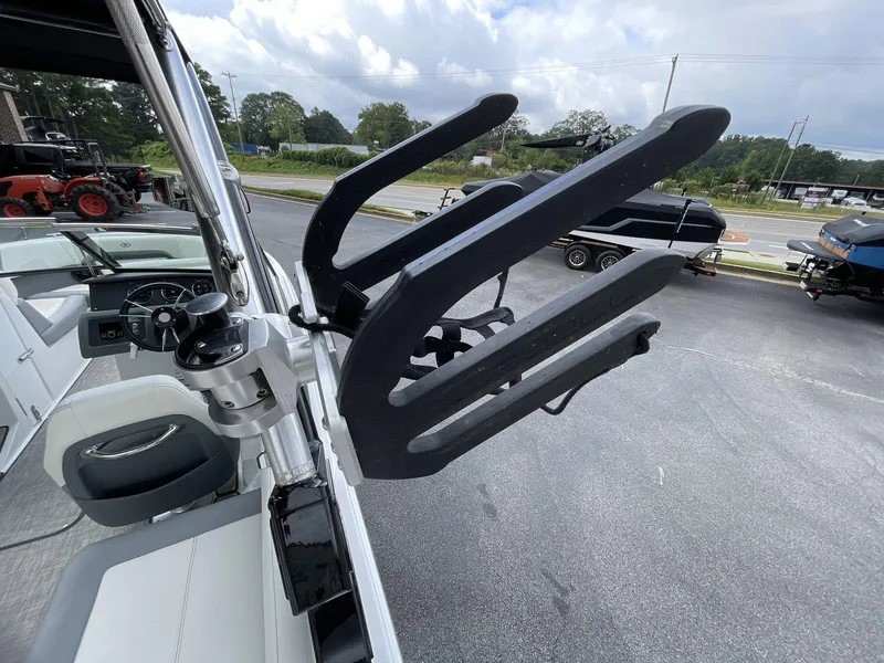 Slide: The Image of 2018 Cobalt CS23 Surf boat with wakeboard rack, parked outdoors. - 16
