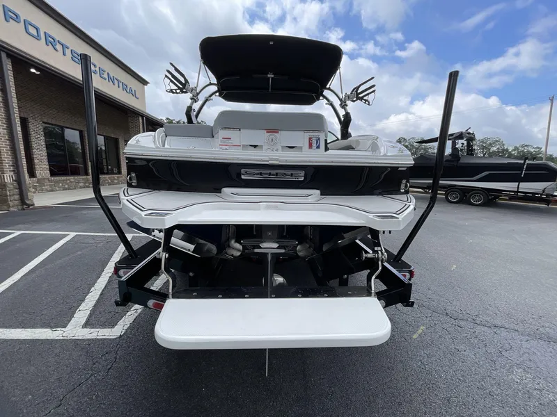 Slide: The Image of 2018 Cobalt CS23 Surf boat rear view at dealership, showcasing swim platform and wakeboard tower. - 4