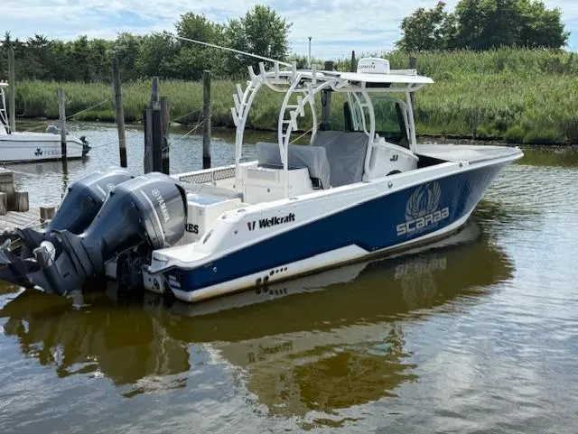 Slide: The Image of 2018 Wellcraft 302 Fisherman boat docked, featuring dual outboard engines and sleek design. - 0