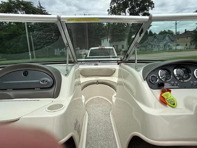 Slide: The Image of 2005 Sea Ray 200 Sport boat interior with dashboard and seating, parked near residential area. - 10
