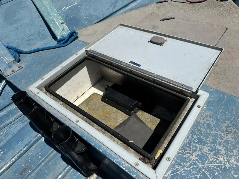 Slide: The Image of Open storage compartment on a 1998 Klamath 14 DLX boat, featuring rod holders and blue interior. - 13