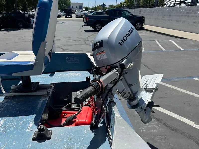 Slide: The Image of 1998 Klamath 14 DLX boat with Honda outboard motor in a parking lot. - 18