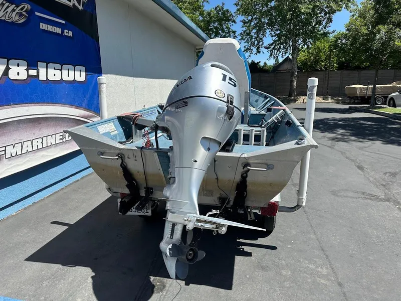 Slide: The Image of 1998 Klamath 14 DLX boat with a 15 HP outboard motor, parked outdoors. - 7