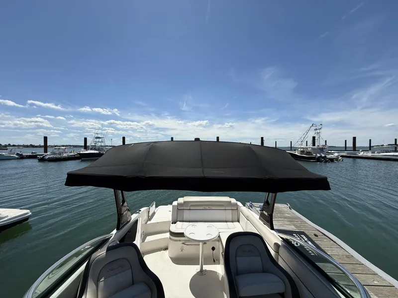 Slide: The Image of 2013 Sea Ray 260 Sundeck boat docked, featuring spacious seating and a black canopy. - 8