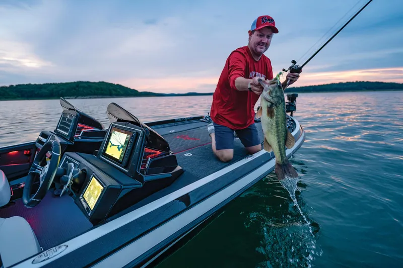 Slide: The Image of Man fishing on a 2023 Ranger Z521R boat at sunset, holding a large fish. - 13