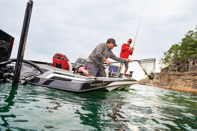 Slide: The Image of 2023 Ranger Z521R boat with two people fishing on a lake near rocky cliffs. - 15