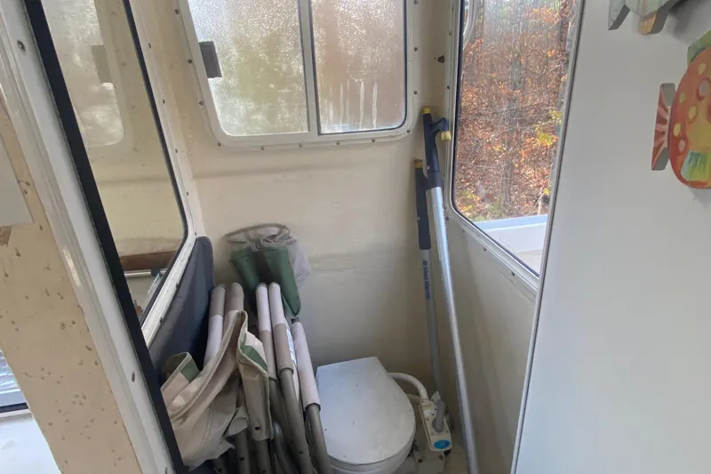 Slide: The Image of Interior of a 2002 C-Dory 25' Cruiser with folded chairs and a portable toilet. - 18