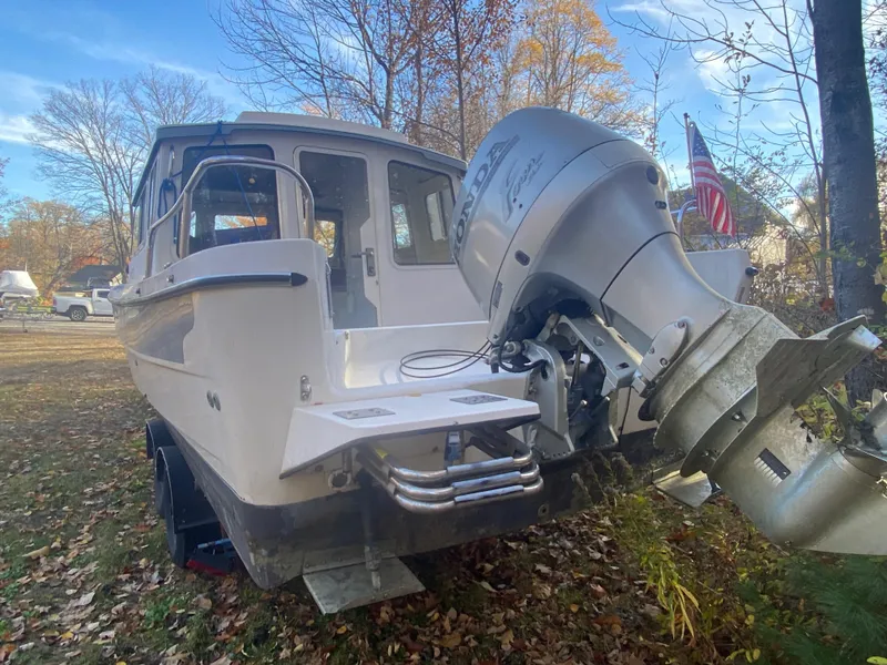 Slide: The Image of 2002 C-Dory 25' Cruiser with Honda outboard motor, parked on a leafy ground. - 19