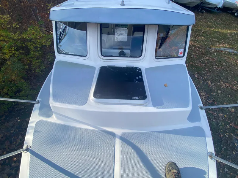 Slide: The Image of 2002 C-Dory 25' Cruiser boat deck with windows and railing, surrounded by foliage. - 8