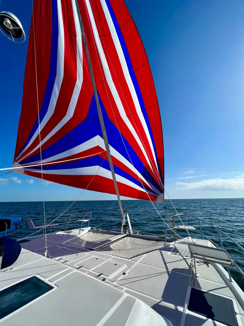 Slide: The Image of Royal Cape Catamarans 530 sailing with vibrant red, white, and blue spinnaker, 2019 model. - 20