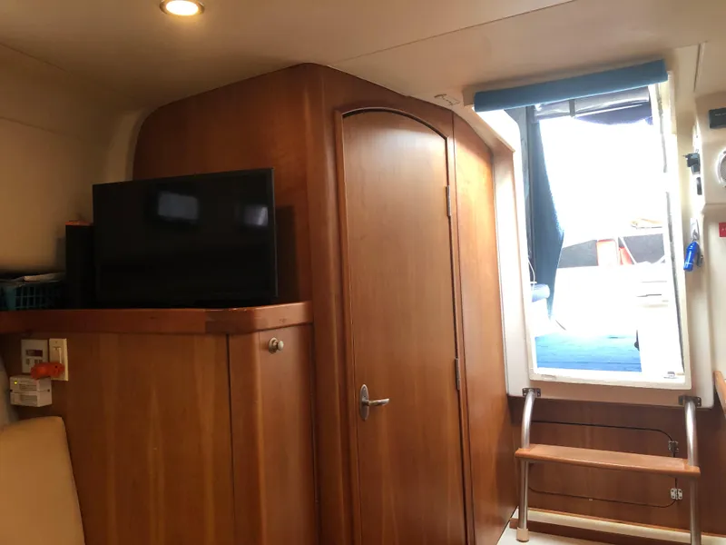 Slide: The Image of 2004 Mainship Pilot 30-II Sedan interior with TV, wooden cabinetry, and window. - 10