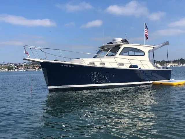 Slide: The Image of 2004 Mainship Pilot 30-II Sedan boat on calm water, blue sky background. - 2