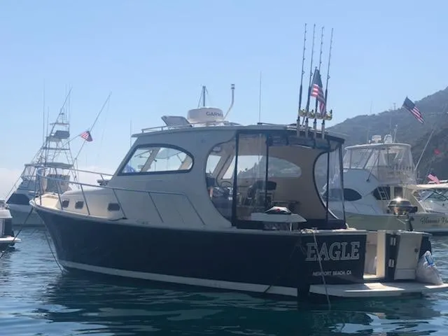Slide: The Image of 2004 Mainship Pilot 30-II Sedan boat docked in a marina with fishing rods. - 3