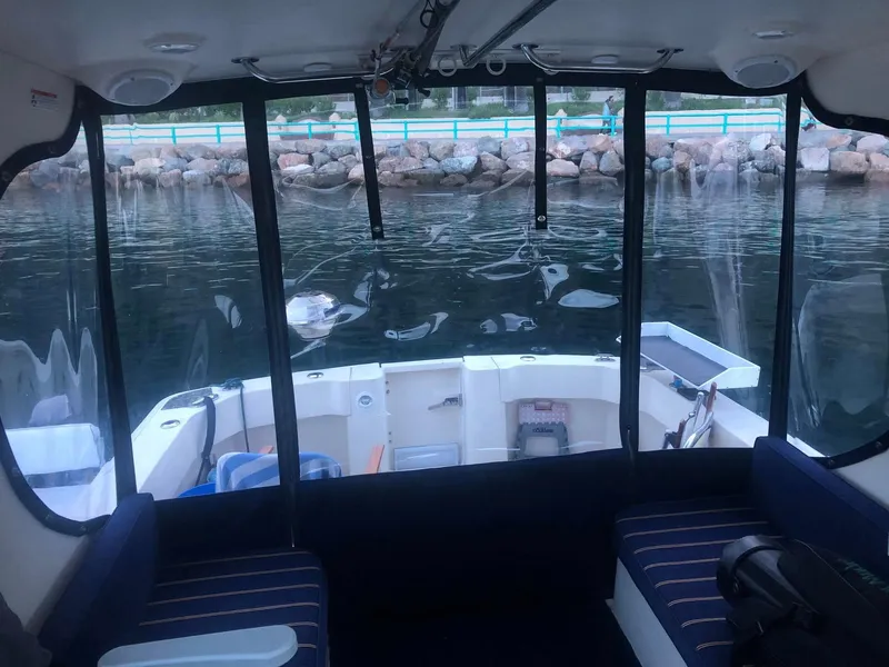 Slide: The Image of Interior view of 2004 Mainship Pilot 30-II Sedan boat, featuring seating and water backdrop. - 6