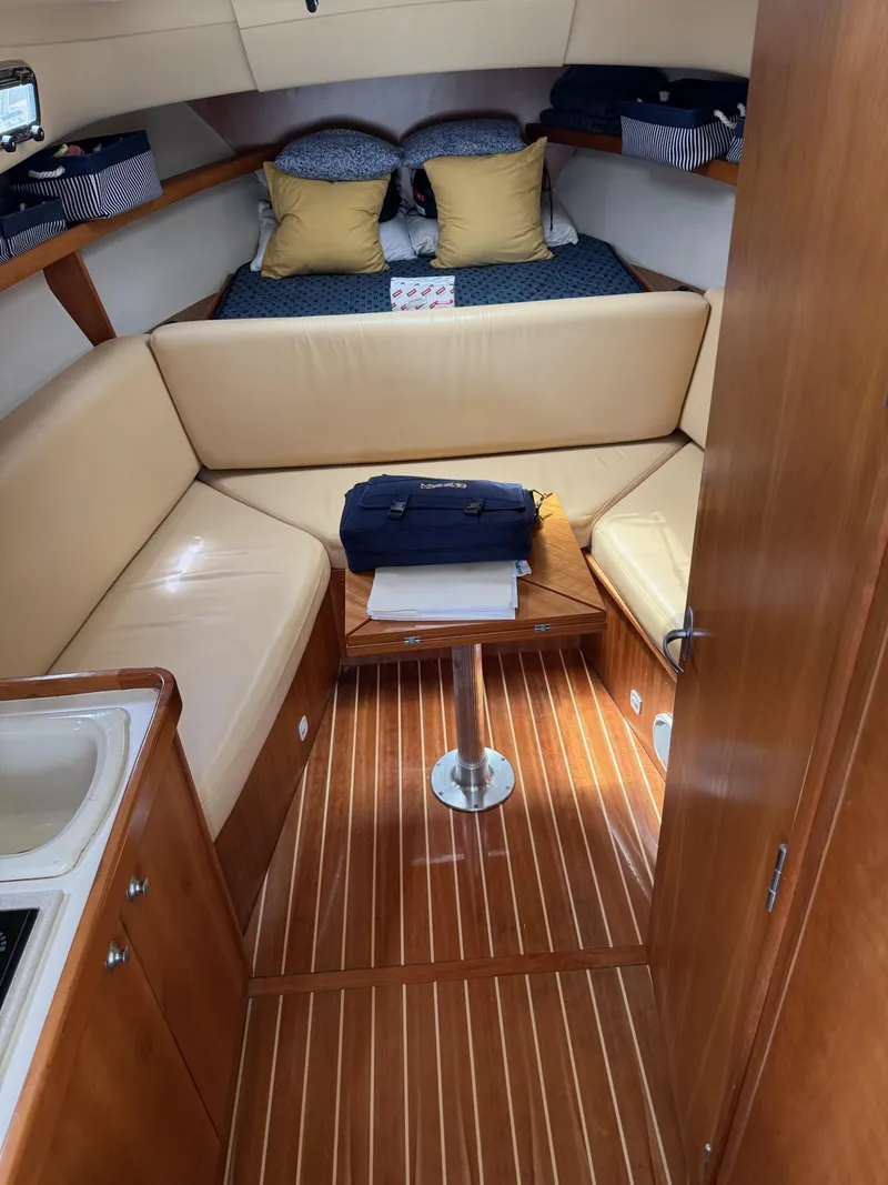 Slide: The Image of 2004 Mainship Pilot 30-II Sedan interior with cozy seating and wooden flooring. - 7