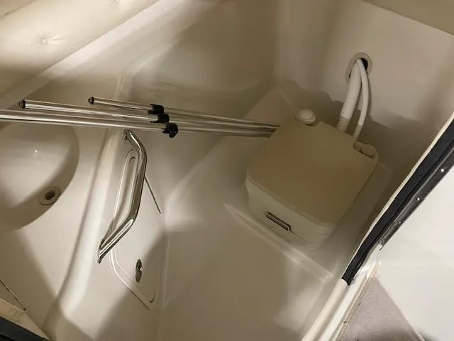 Slide: The Image of 2006 Sea Ray 240 Sundeck interior with portable toilet and metal poles. - 10